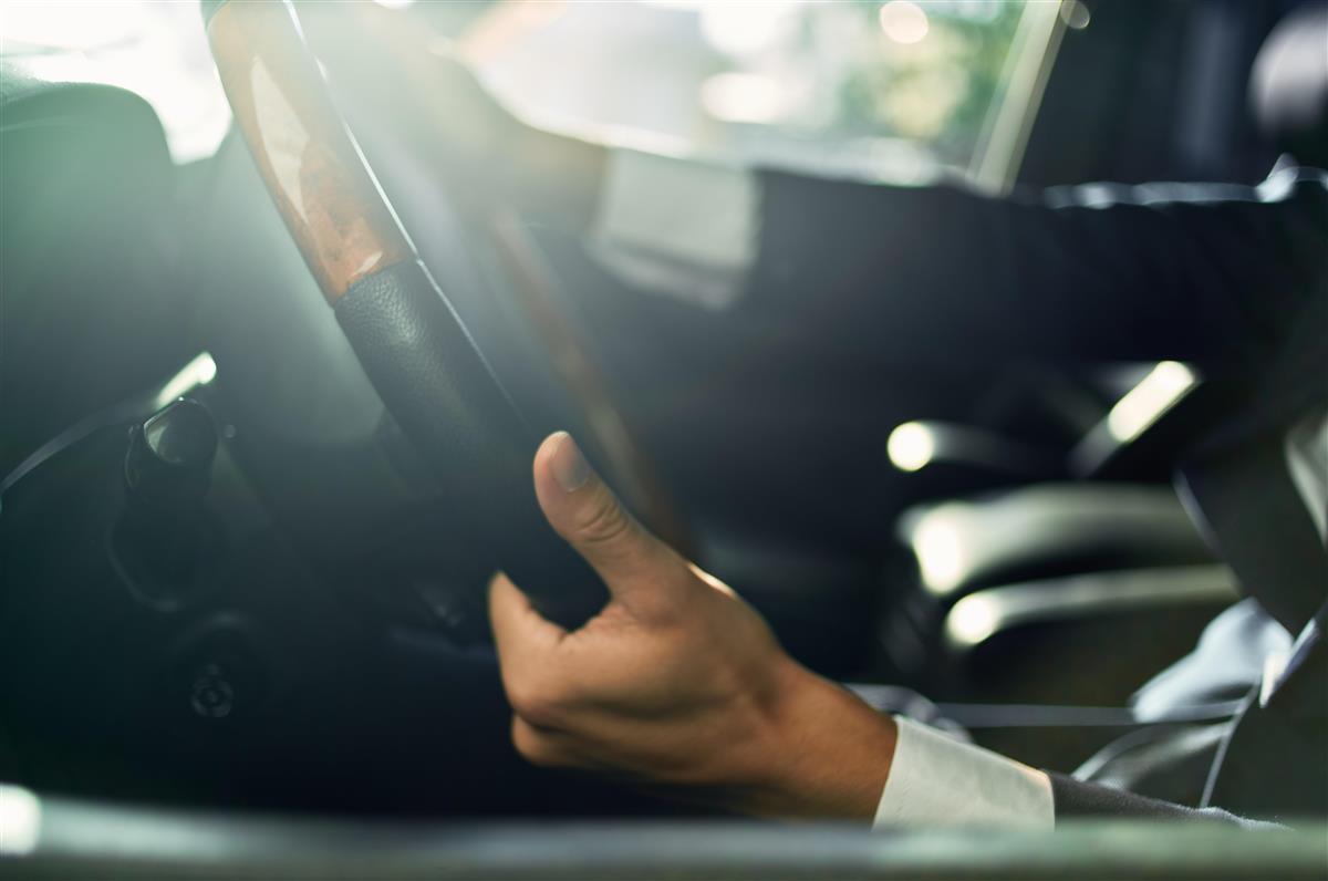 Ein person som kjører ein minibuss. Kun ratt og hender viser. - Klikk for stort bilete